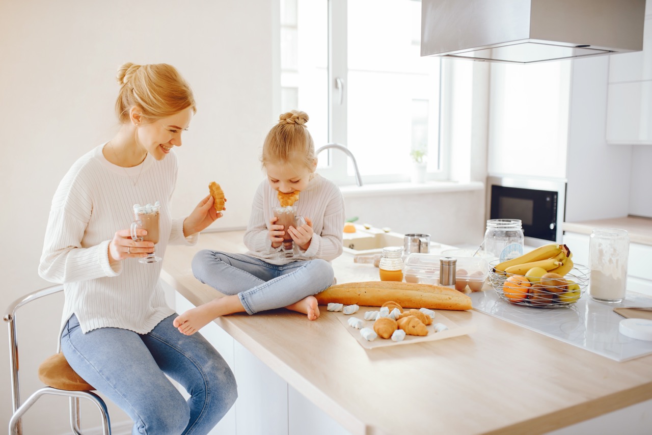 Happy mother and daughter enjoying coffee time in a clean kitchen